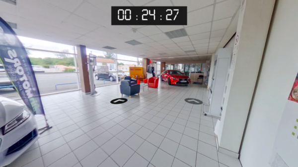 Ecran du serious game de sécurité routière de Pro In Sec. On voit une interface de navigation en 360 degrés dans une succursale automobile. Il y a aussi un chronomètre affiché en haut de l'image.